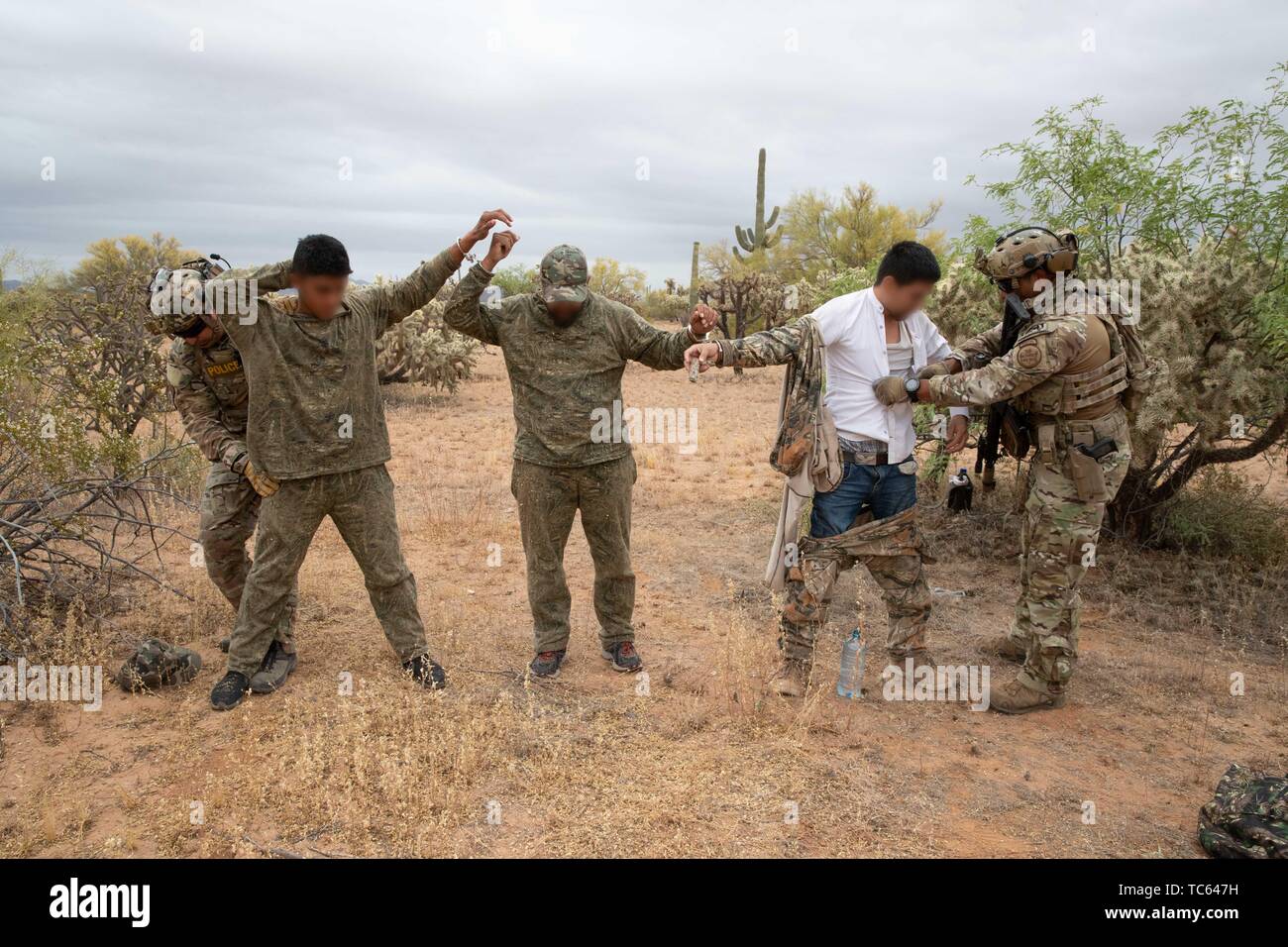 U.S. Border Patrol search a group of illegal migrants after they were apprehended crossing from Mexico on the Tohono Oʼodham Indian Reservation May 22, 2019 near Pisinemo, Arizona. The faces are obscured by the Border Patrol to protect their identity. Stock Photo