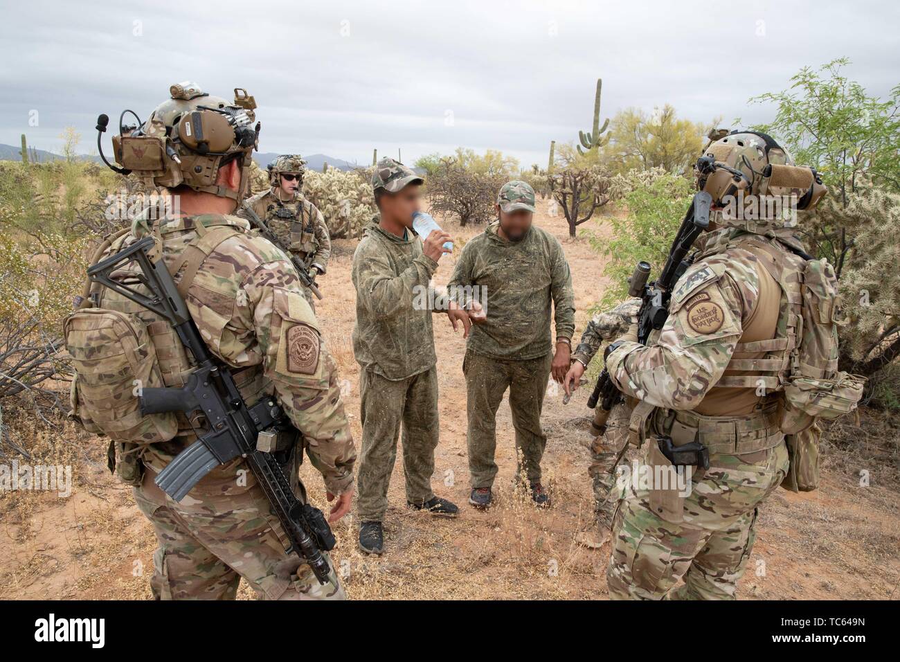 U.S. Border Patrol provide water to a group of illegal migrants after they were apprehended crossing from Mexico on the Tohono Oʼodham Indian Reservation May 22, 2019 near Pisinemo, Arizona. The faces are obscured by the Border Patrol to protect their identity. Stock Photo