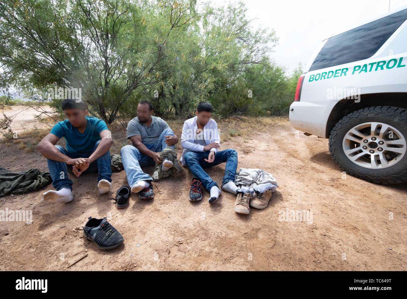 U.S. Border Patrol agents detain a group of illegal migrants after they crossed from Mexico on the Tohono Oʼodham Indian Reservation May 22, 2019 near Pisinemo, Arizona. The faces are obscured by the Border Patrol to protect their identity. Stock Photo