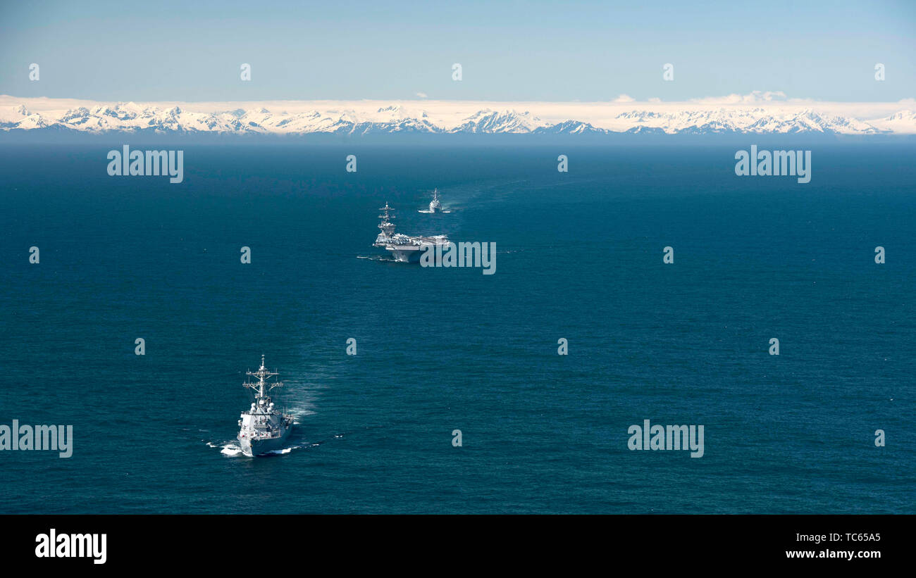 The U.S. Navy Nimitz-class nuclear powered aircraft carrier USS Theodore Roosevelt is escorted by the Arleigh Burke-class guided-missile destroyer USS Russel, front, and the Arleigh Burke-class guided-missile destroyer USS John Finn, rear, during exercise Northern Edge 2019 May 24, 2019 in the Gulf of Alaska. Stock Photo