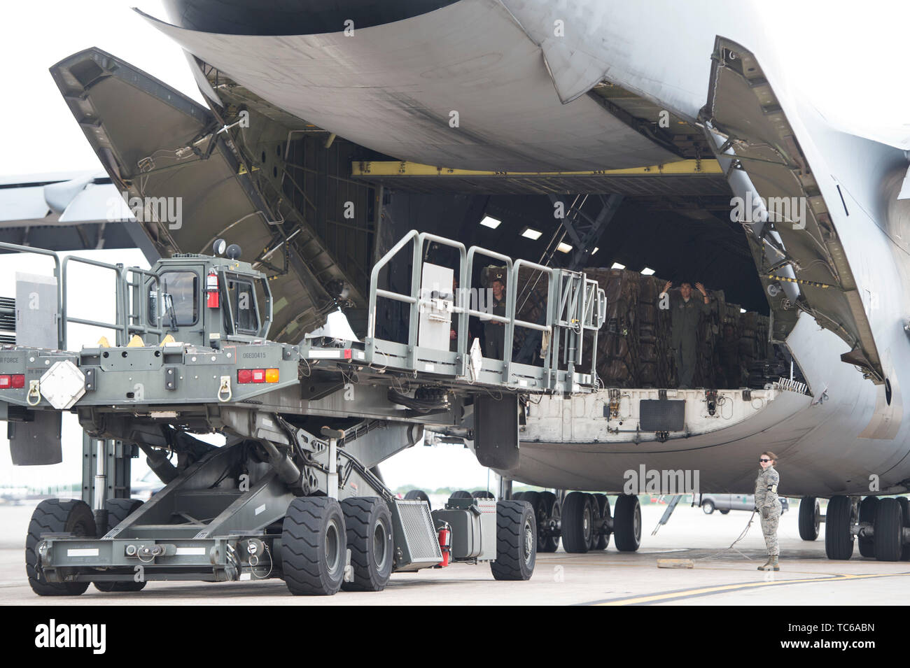 A loadmaster from the 312th Airlift Squadron guides a 60K Loader to the C-5 Galaxy in St. Paul, Minn., May 22, 2019. The Airmen are taking part in the Denton Program which is a Department of Defense transportation program that moves humanitarian cargo, donated by the U.S. based Non-Governmental Organizations to developing nations to ease human suffering.   (U.S. Air National Guard photo by Amy M. Lovgren) Stock Photo