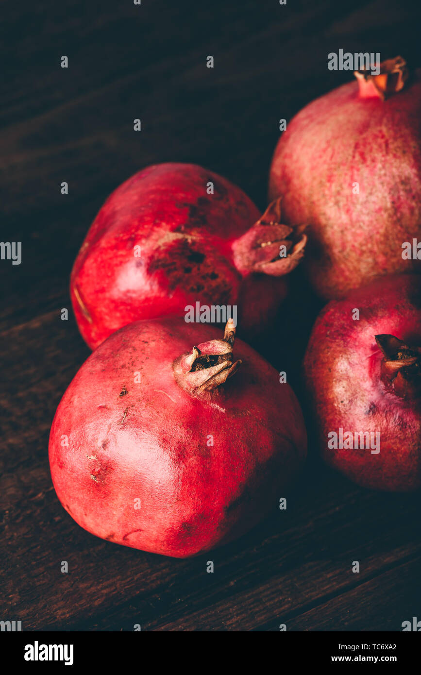 Four ripe pomegranate on rustic wooden table Stock Photo
