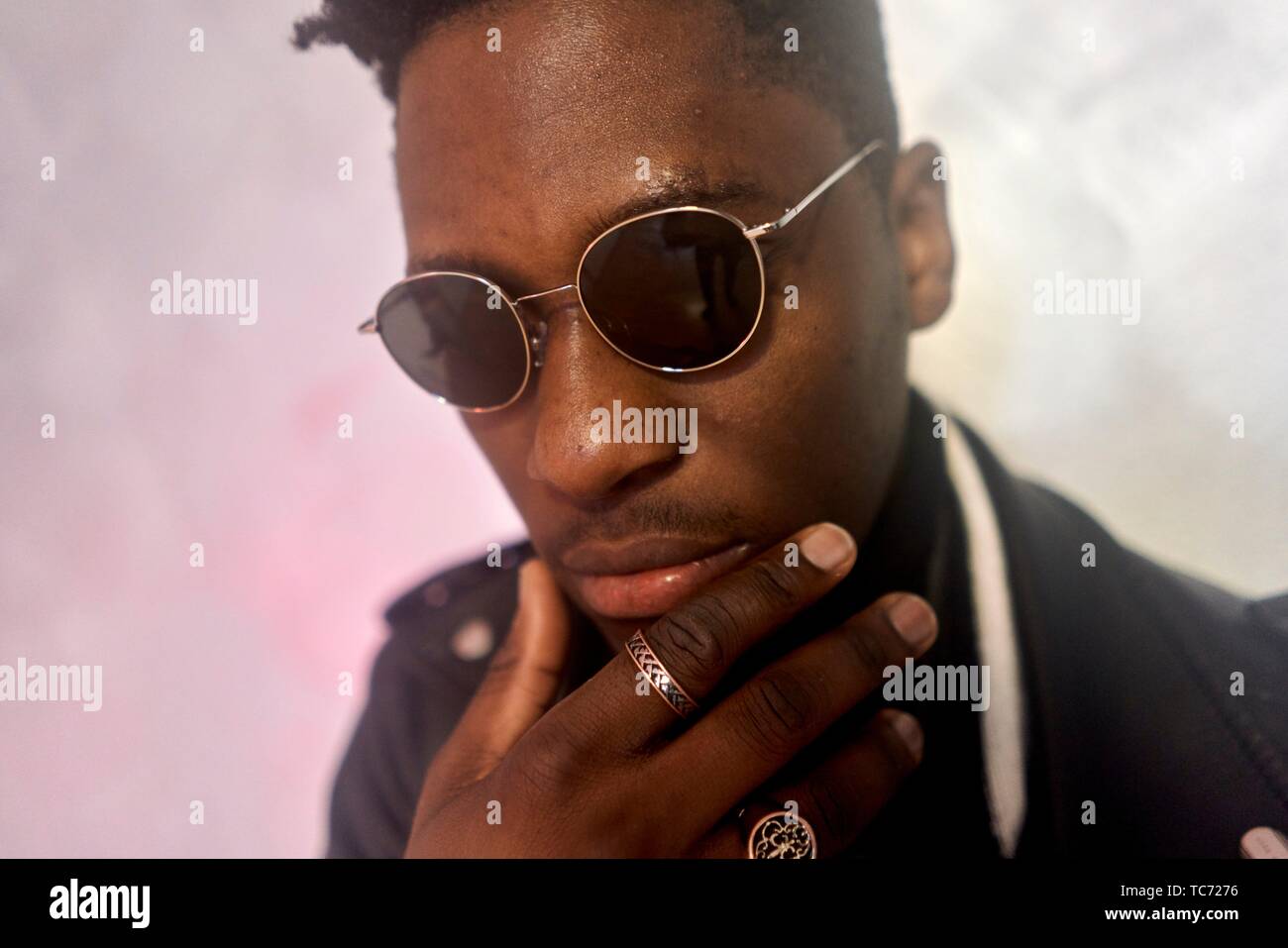 portrait of young African man wearing sunglasses indoors fingers