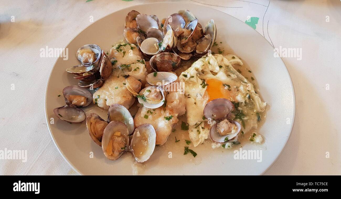 Monkfish stew with clams and egg poche. A Mediterranean delicacy. Stock Photo