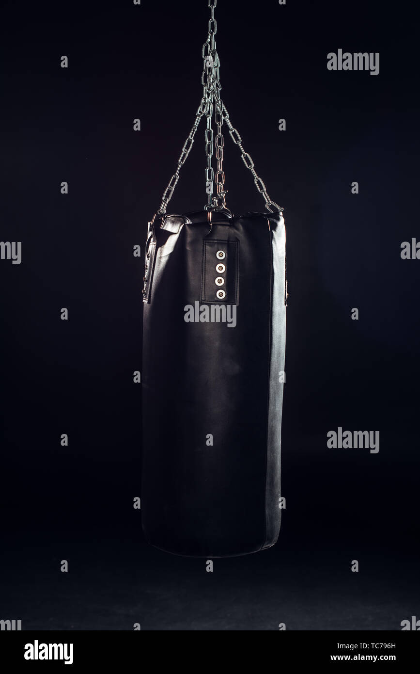 Leather punching bag hanging on steel chains on black Stock Photo Alamy