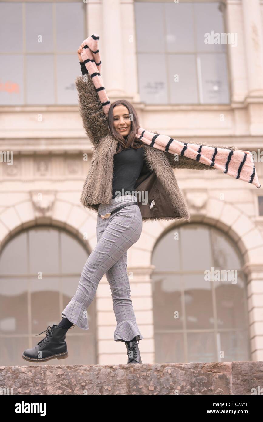 Playful Woman In Fashionable Winter Clothes Playing With Scarf