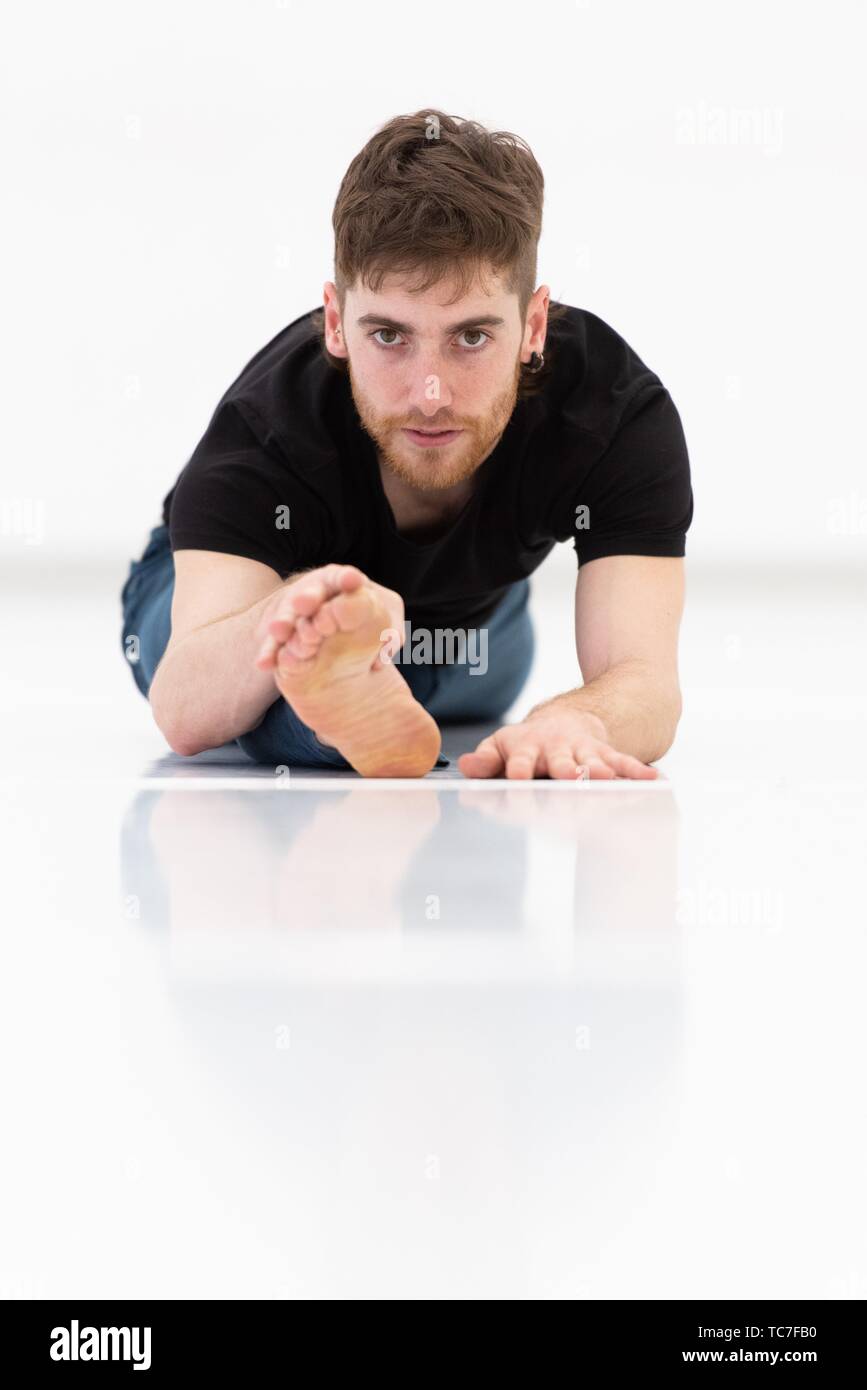 Casual dressed young adult man stretching on white background. Stock Photo
