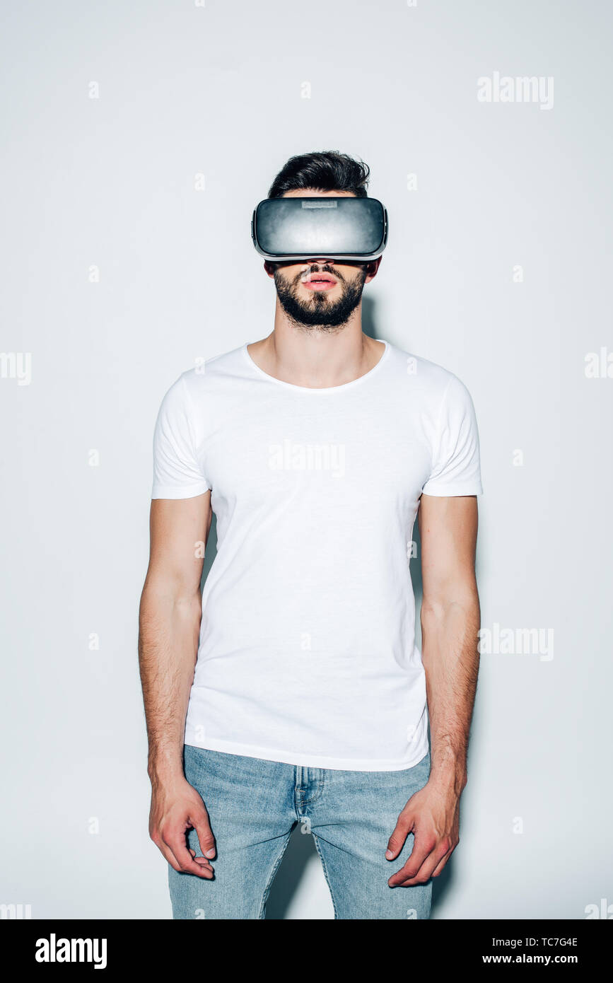 bearded man wearing virtual reality headset while standing on white Stock Photo