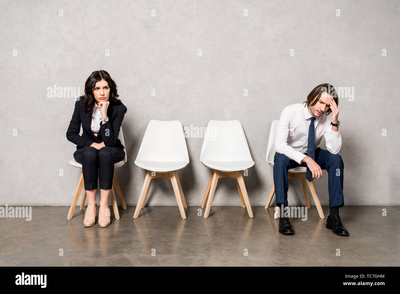 worried man sitting near attractive brunette woman on chair Stock Photo