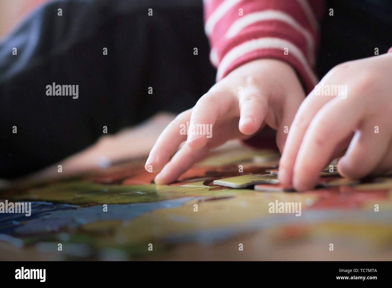 Toddler hand doing a puzzle Stock Photo - Alamy