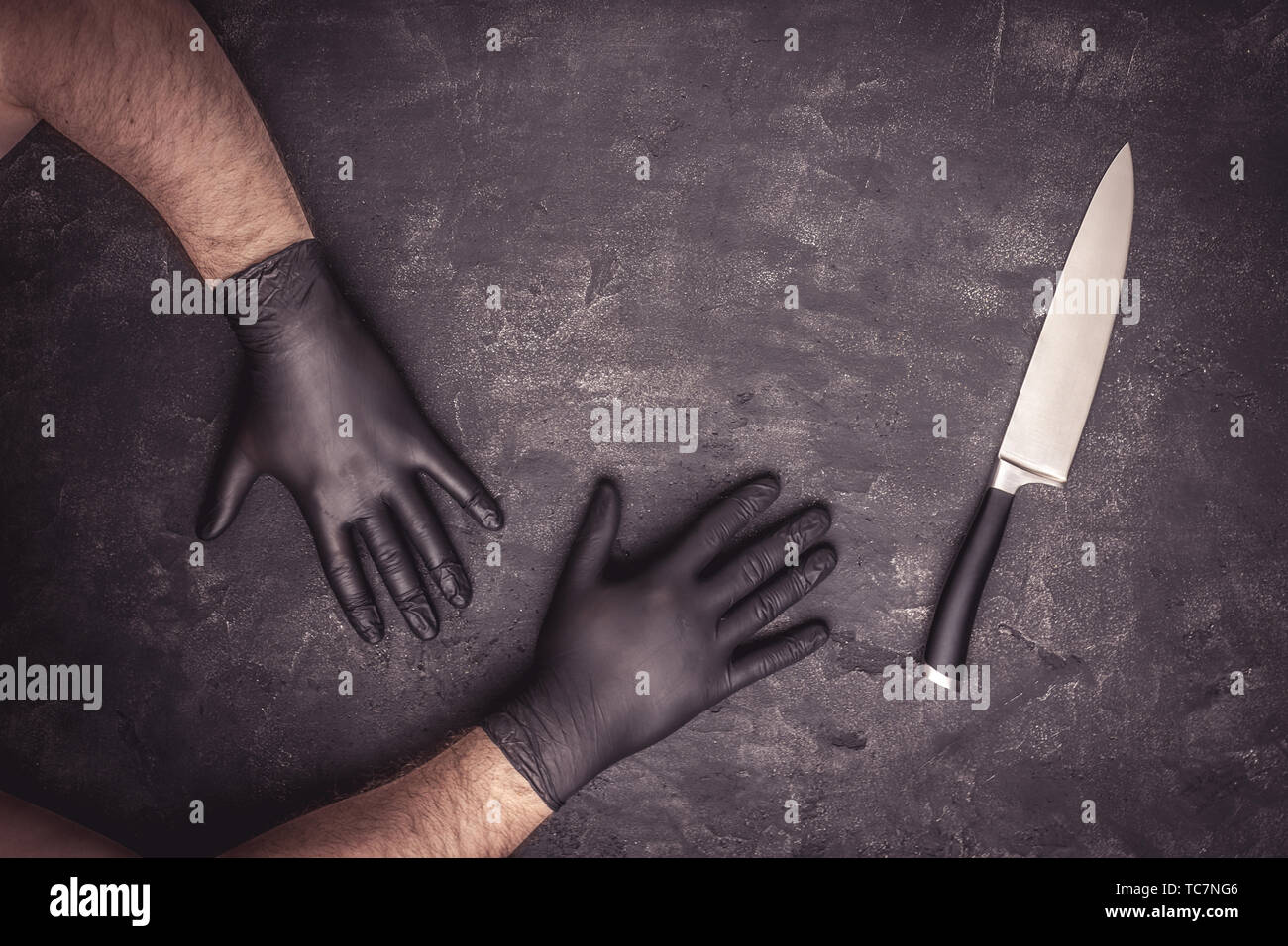 Big Knife and Male Hands with Black Latex Gloves on Dark Background Stock Photo