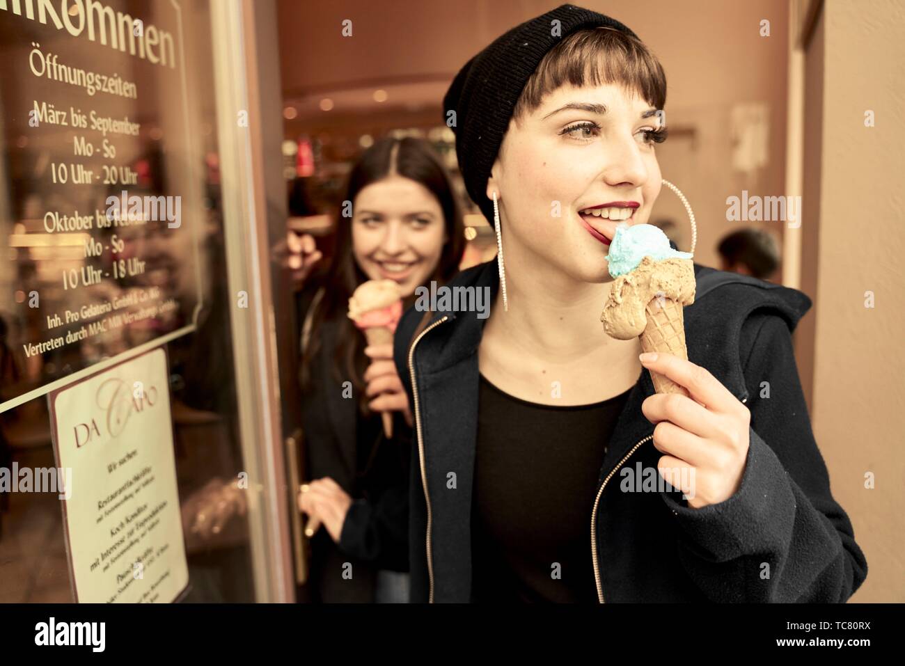 two women with ice cream cones coming out of ice café, in city Cottbus