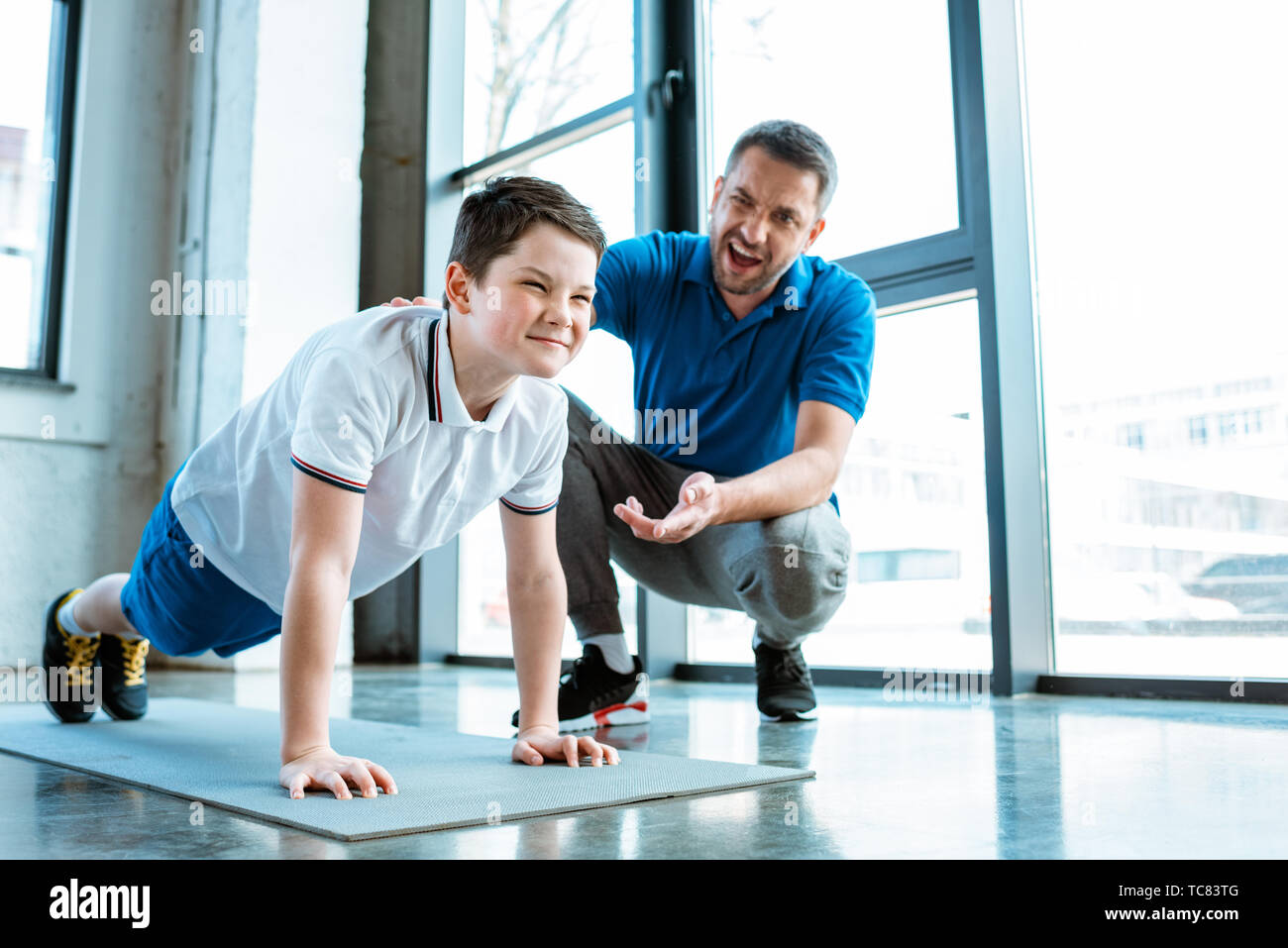 father helping son with push up exercise at gym Stock Photo