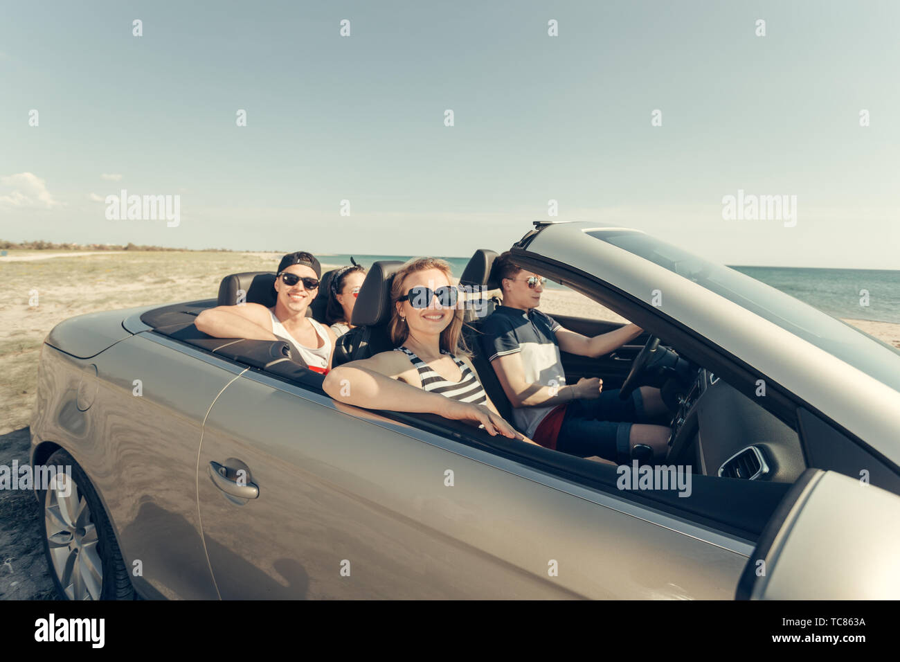 Smiling friends driving car near the sea and having fun Stock Photo - Alamy