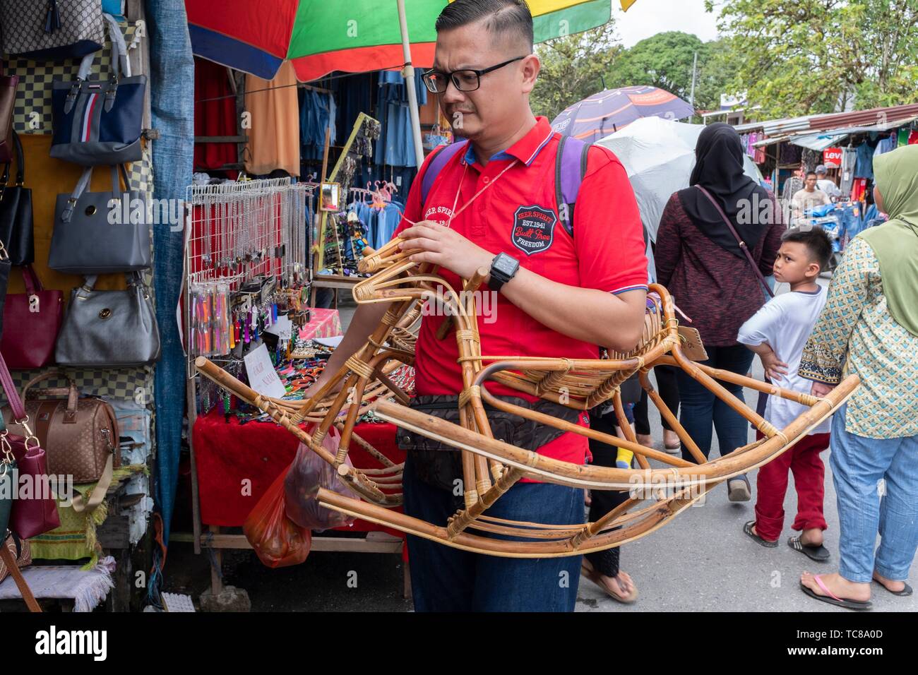 A man carrying a rotan rocking chair for kid at Serikin Malaysia