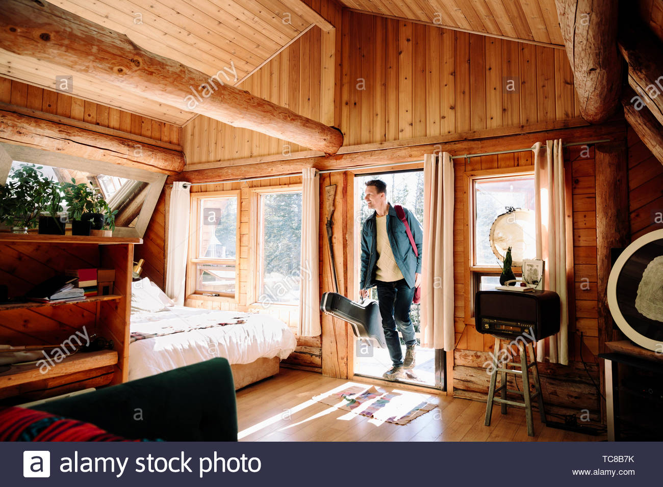 Man with guitar case arriving at cabin Stock Photo Alamy
