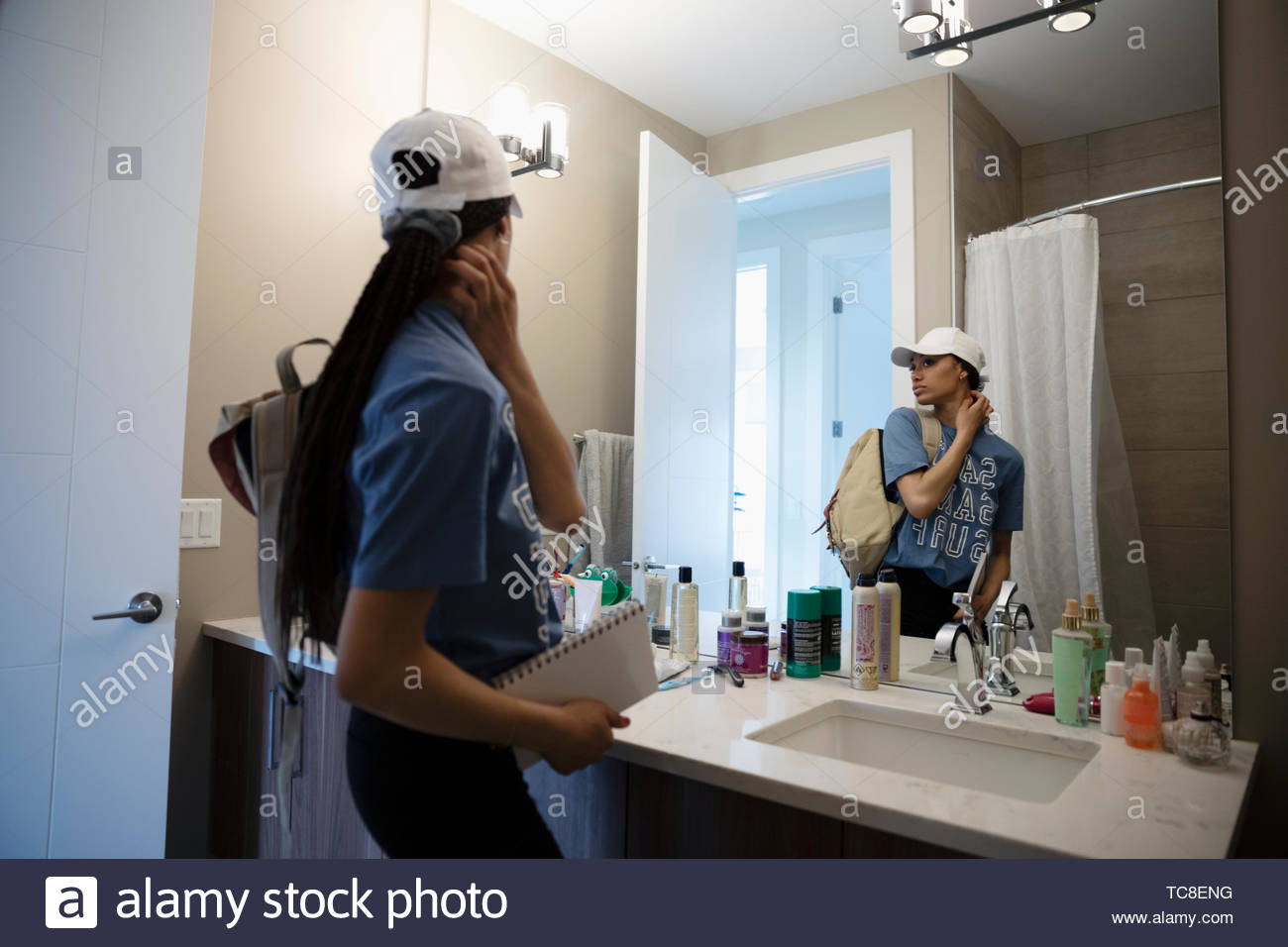 Teenage girl getting ready for work at bathroom mirror Stock Photo