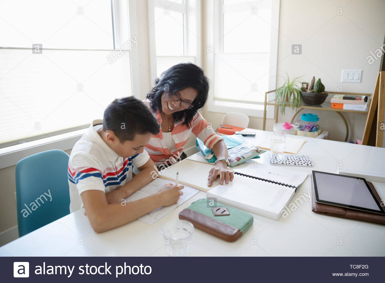 Mother helping son doing homework at table Stock Photo