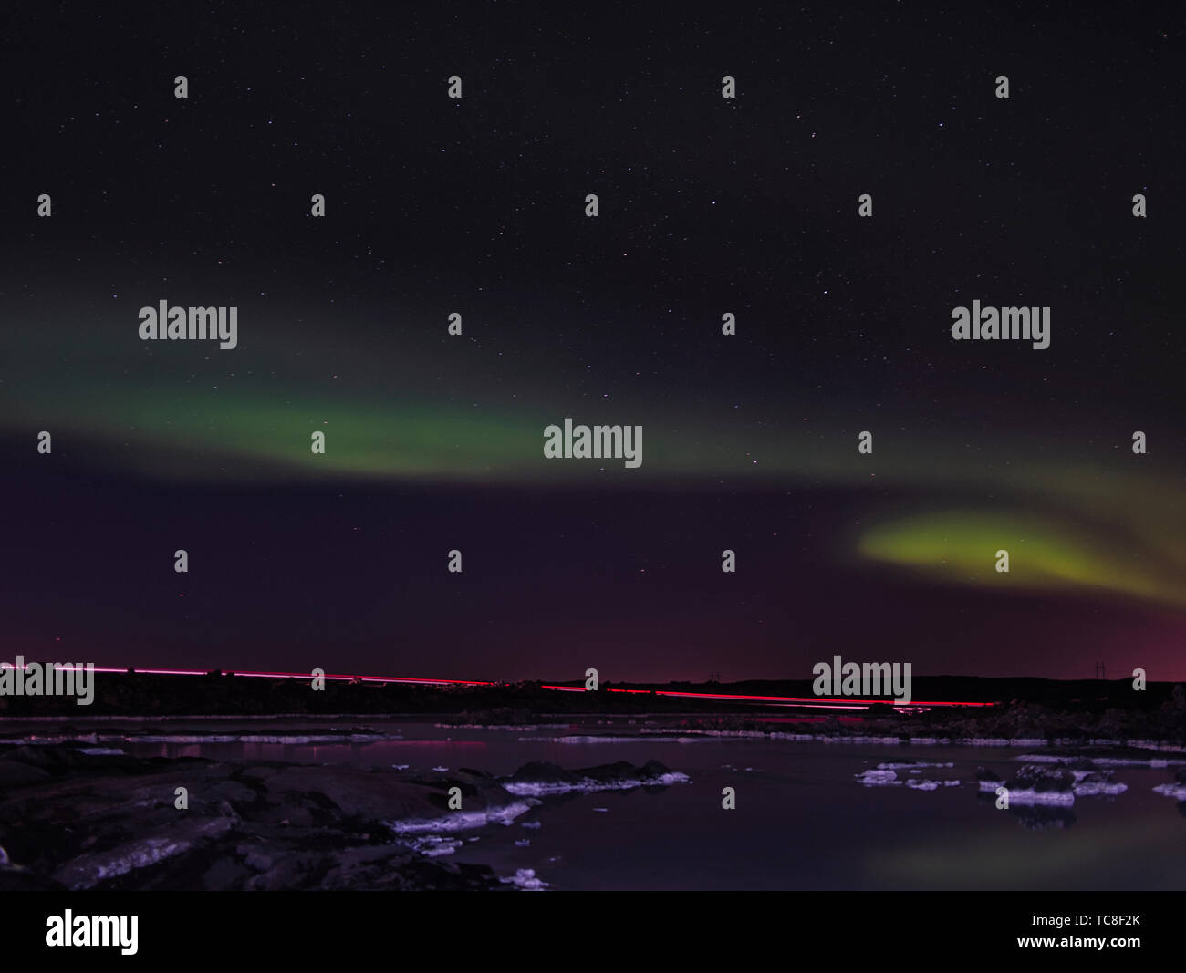 A trail of lights from a car and the northern lights over the Blue Lagoon in island Stock Photo
