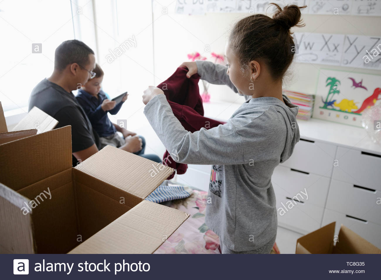 Girl sorting and donating clothes in bedroom Stock Photo