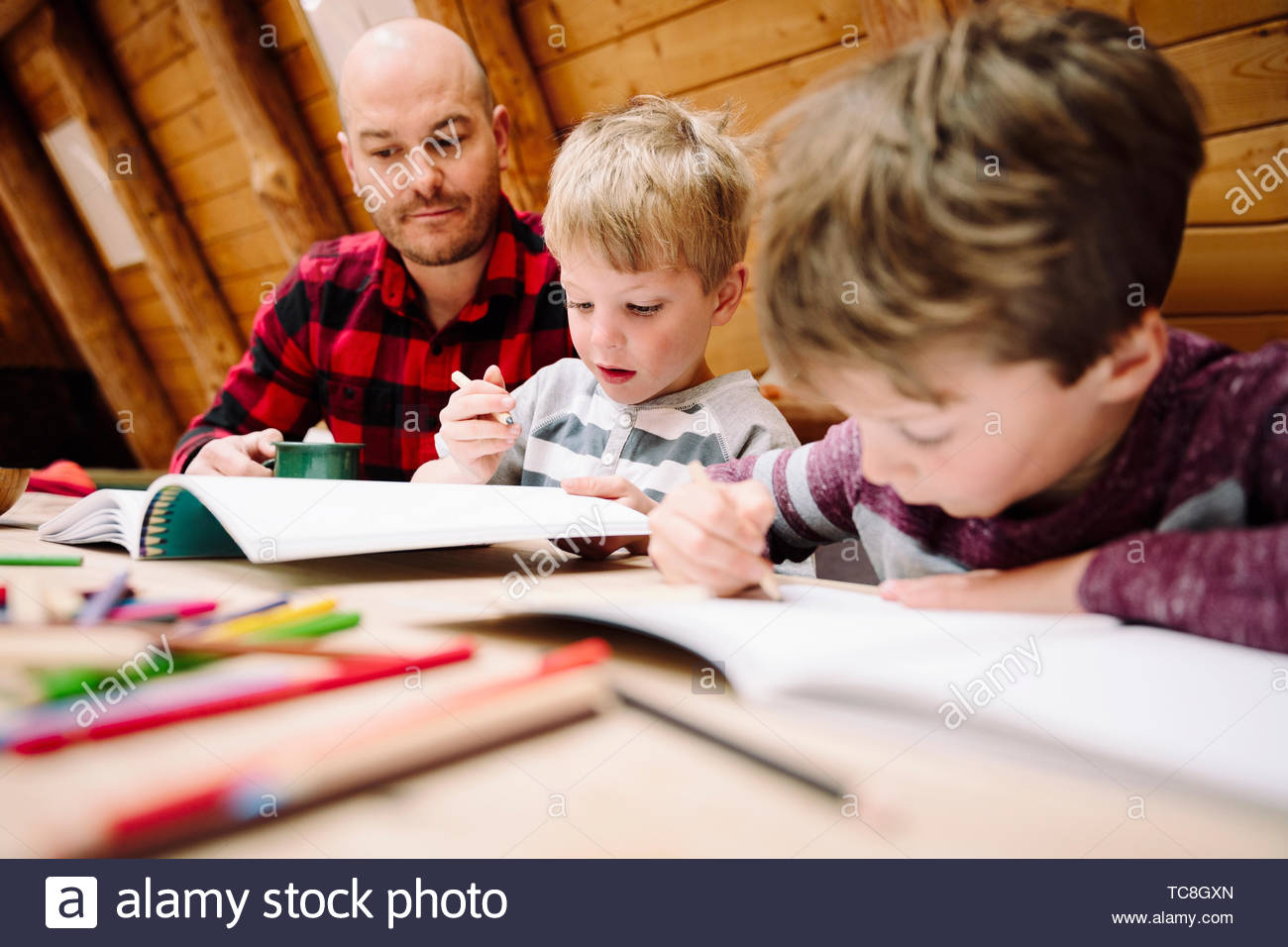 Father and sons coloring at cabin table Stock Photo