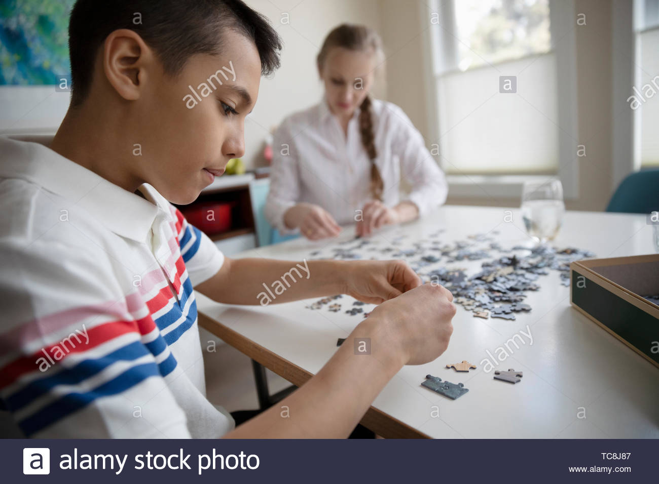 Boy assembling jigsaw puzzle at table Stock Photo