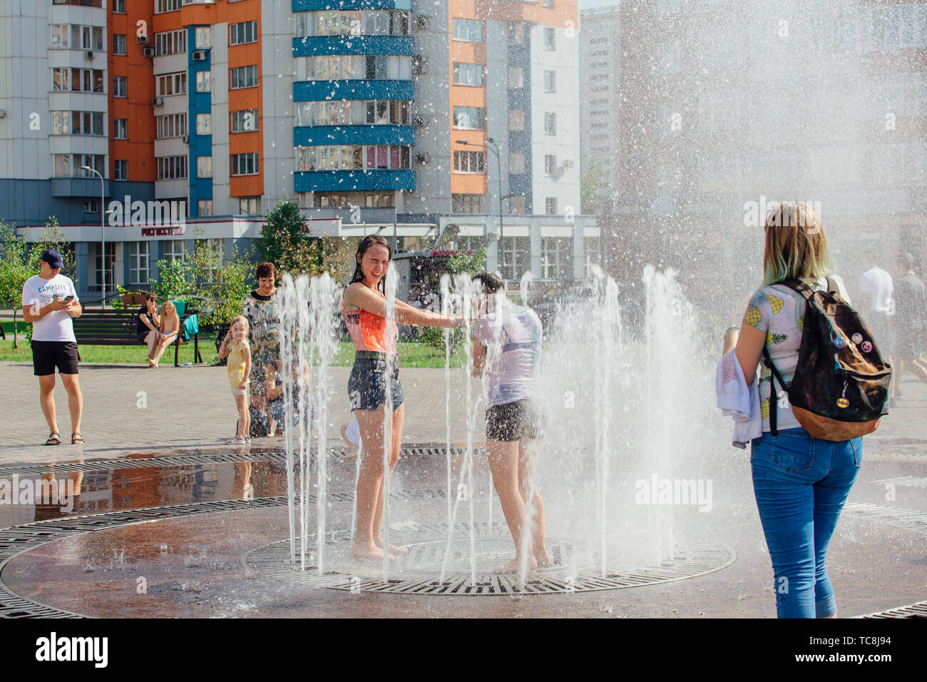 Novokuznetsk, Kemerovo Region, Russia - August 04, 2018: Happy teenagers splashing in a water of a city fountain and enjoying the cool streams of Stock Photo