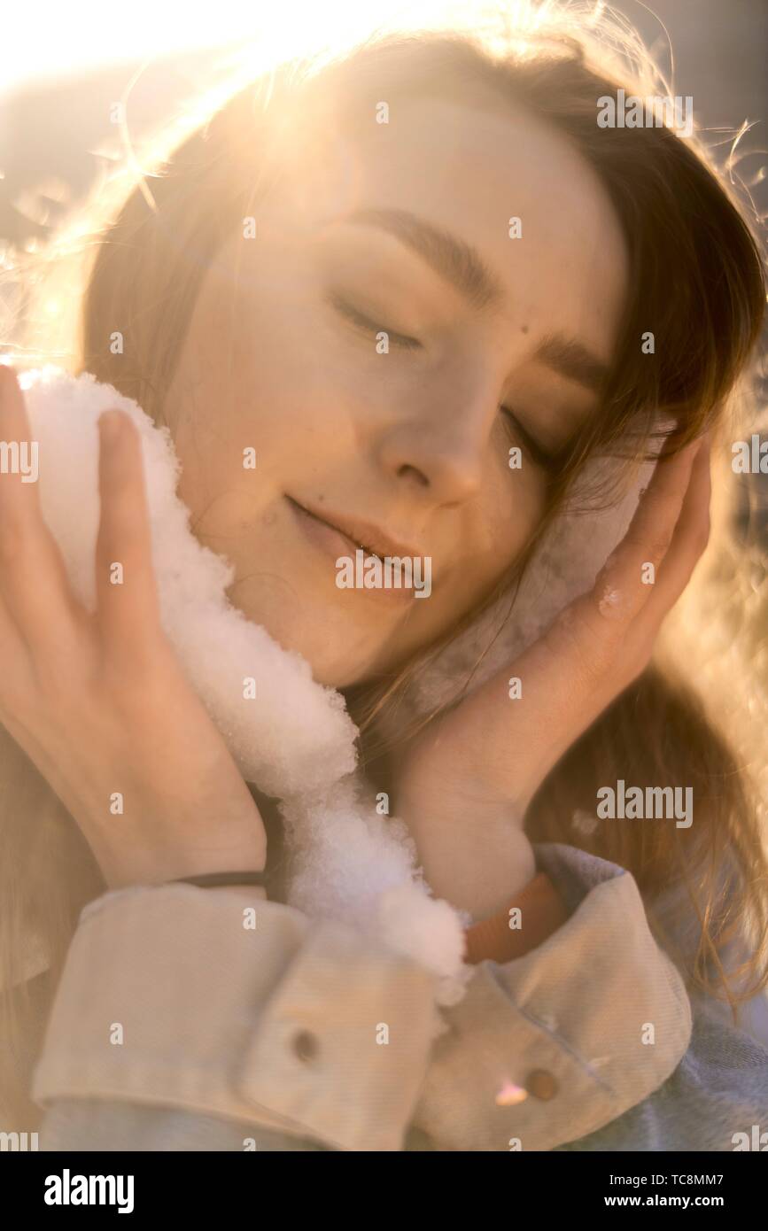emotive woman with snow in hands cooling down her head Stock Photo