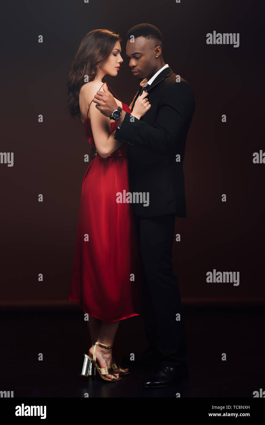 beautiful seductive interracial couple in formal wear posing isolated on  black Stock Photo - Alamy