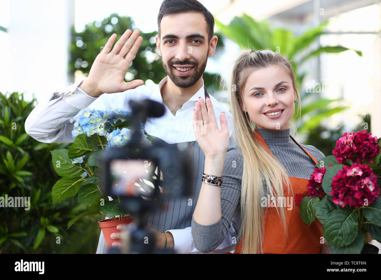 Man and Woman Blogger with Flower Waving to Camera Stock Photo