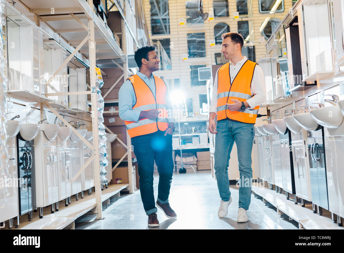 smiling multicultural warehouse workers talking in plumbing department Stock Photo