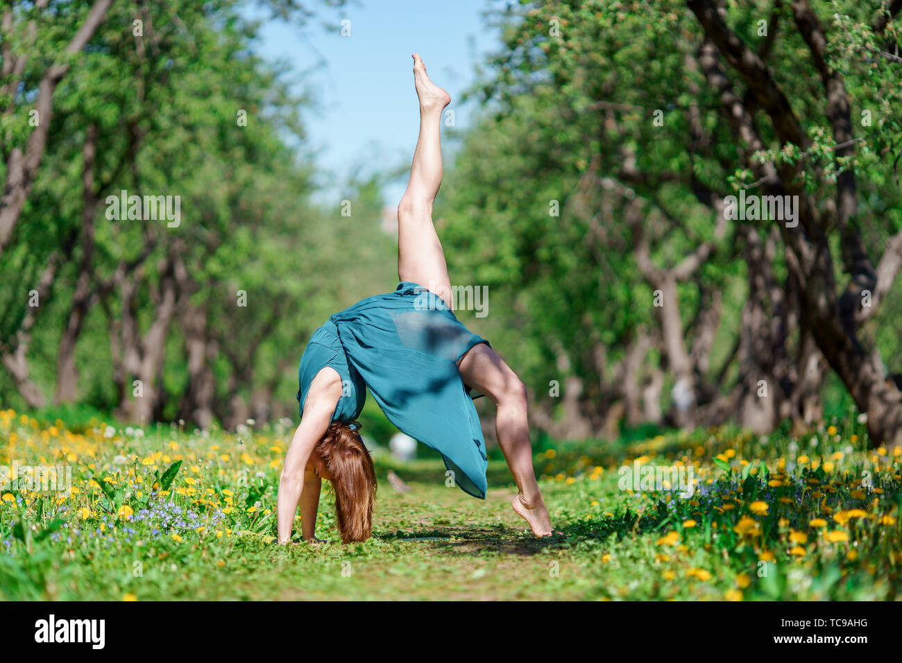 Photo of girl standing on her arms, with raised leg in long green dress  doing yoga in forest on summer day Stock Photo - Alamy