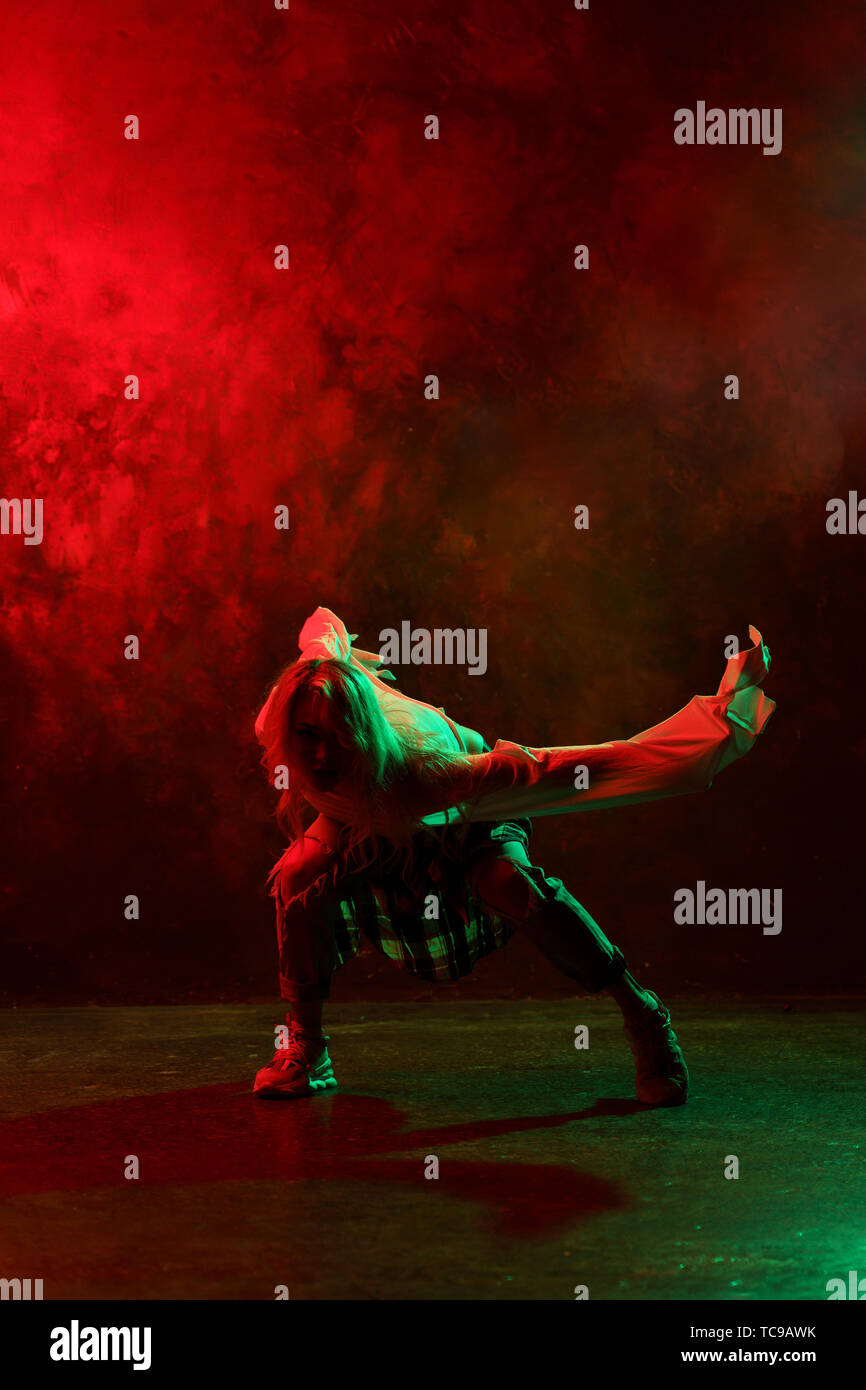 Photo of woman in jeans dancing modern dances on red-green background