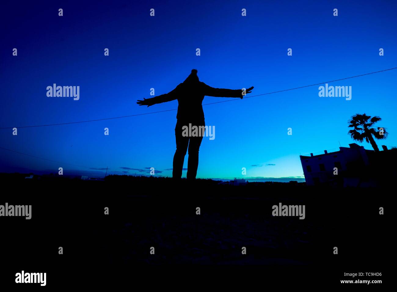 Silhouette of a girl with open arms against blue sunset sky. Valencia, Spain Stock Photo