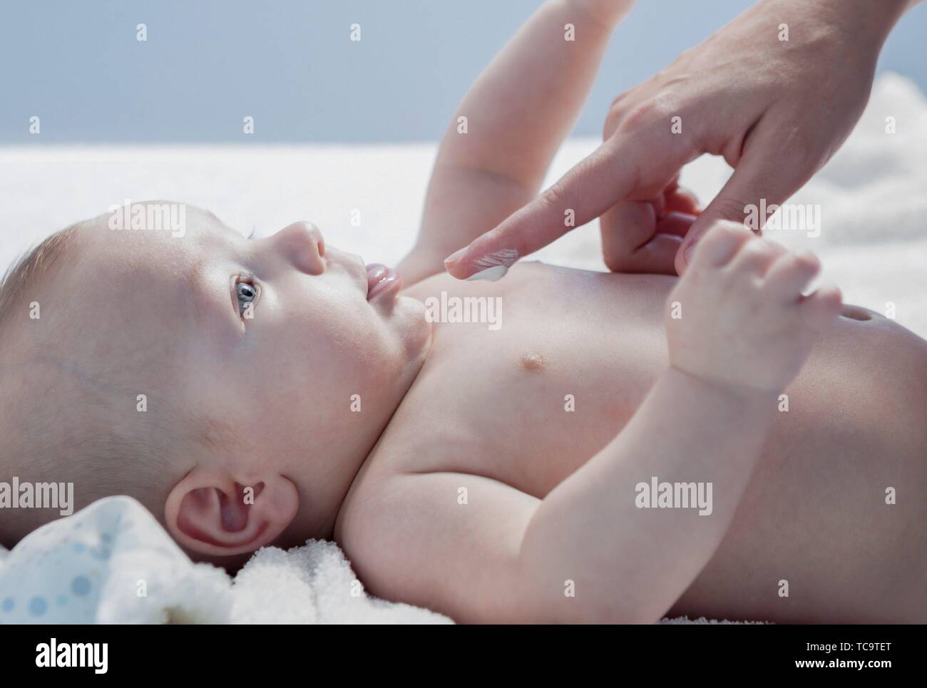 Applying cream over three months baby boy after bath. Bathing and skin sare for babies. Stock Photo