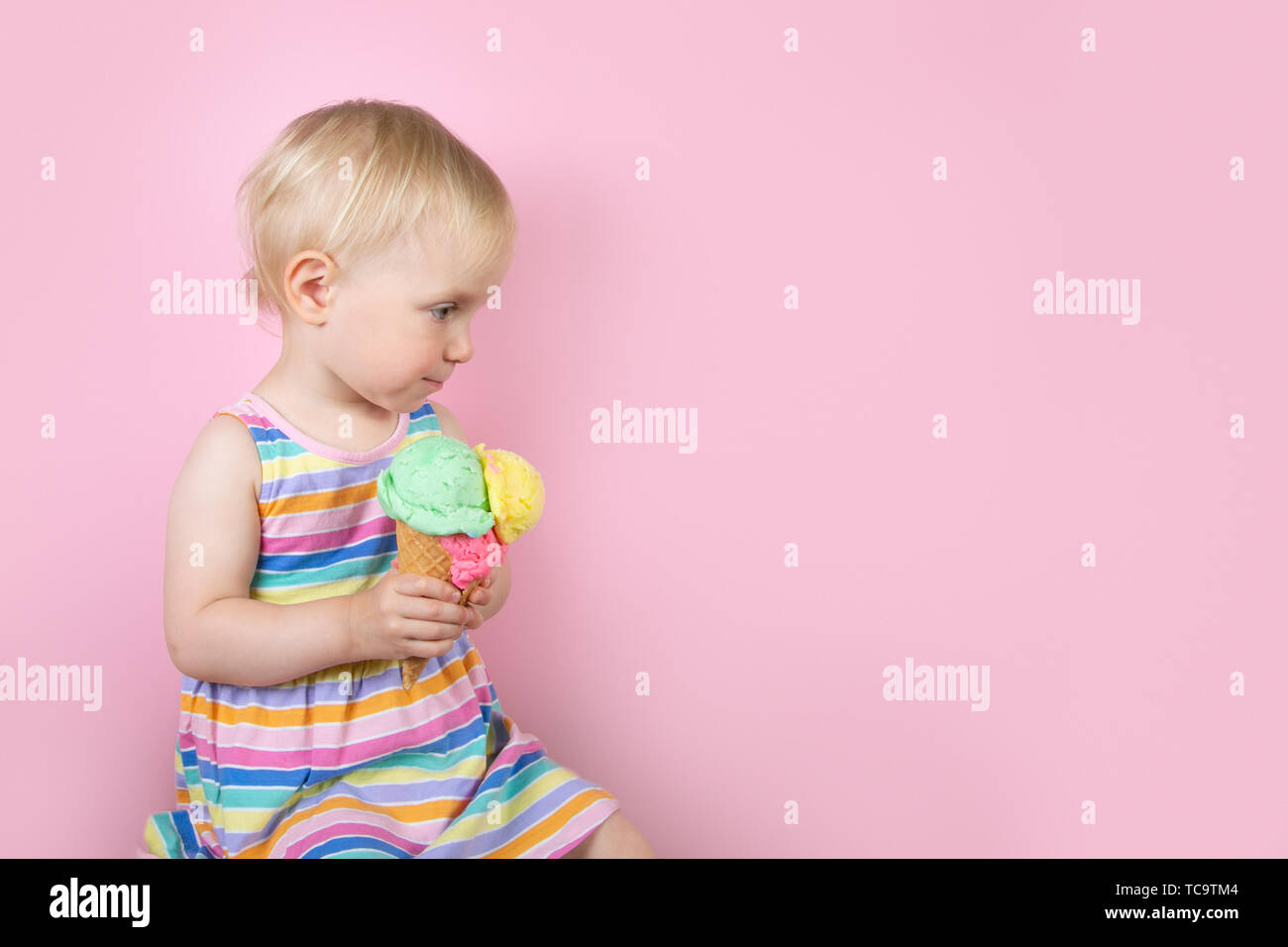 Pretty girl eating ice cream in front of pink background Stock Photo
