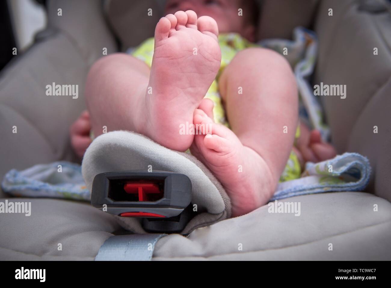 Newborn baby feet over at i-size baby car seat. Low angle shot. Stock Photo