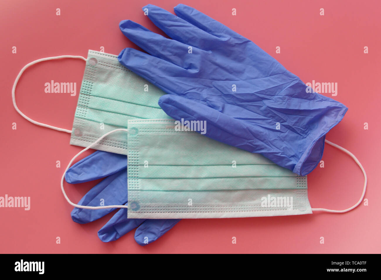 Disposable medical mask and latex gloves. Medical kit essential disposable items. Medical protection of the face and hands. Pink background. Stock Photo