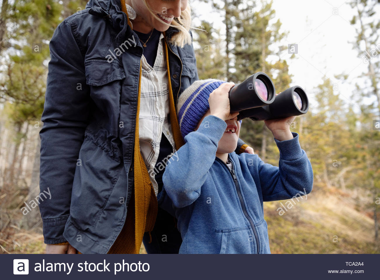 Mother and son with binoculars bird watching, hiking in woods Stock Photo