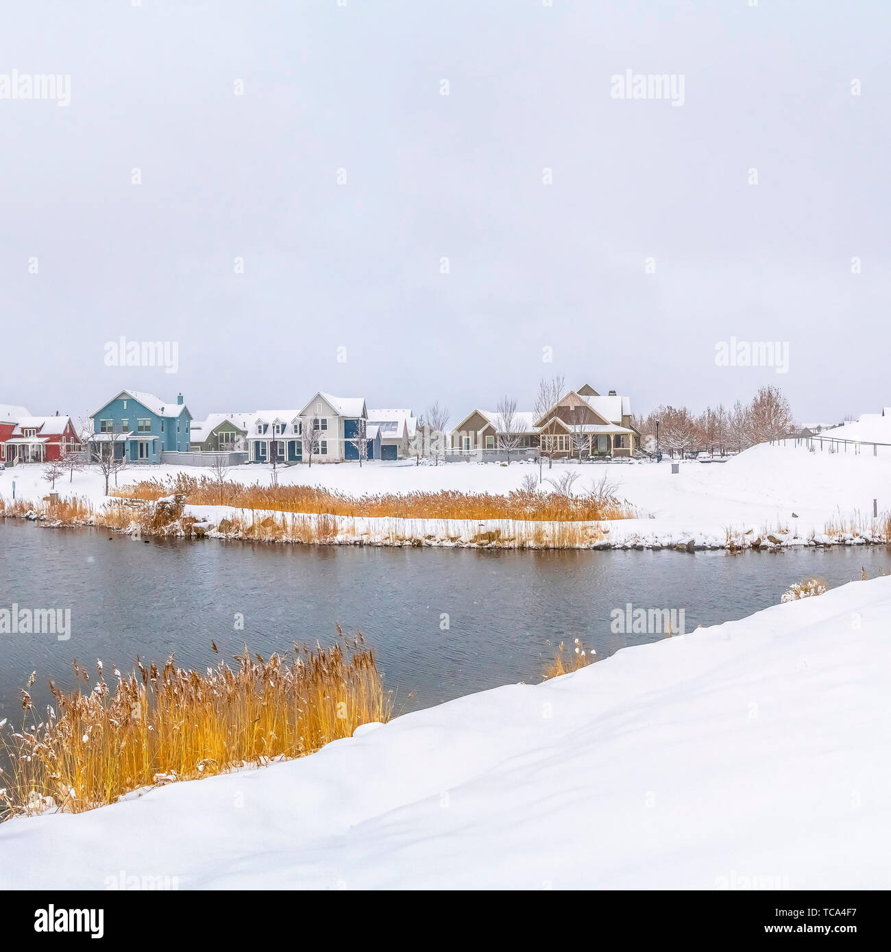 Frame Square Panorama of a silvery lake with distant houses against cloudy sky in winter Stock Photo