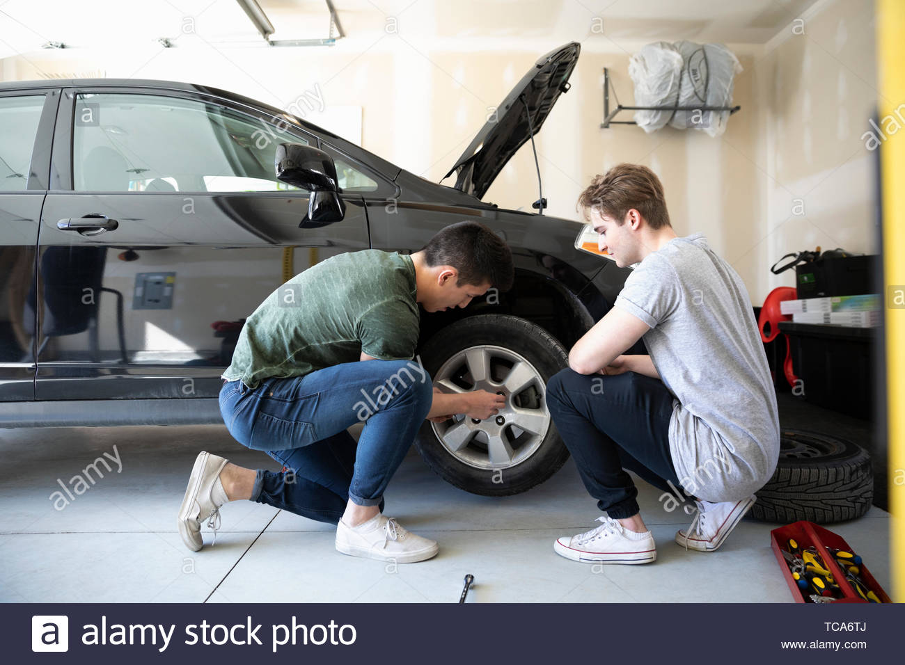 Young men changing car tire in garage Stock Photo