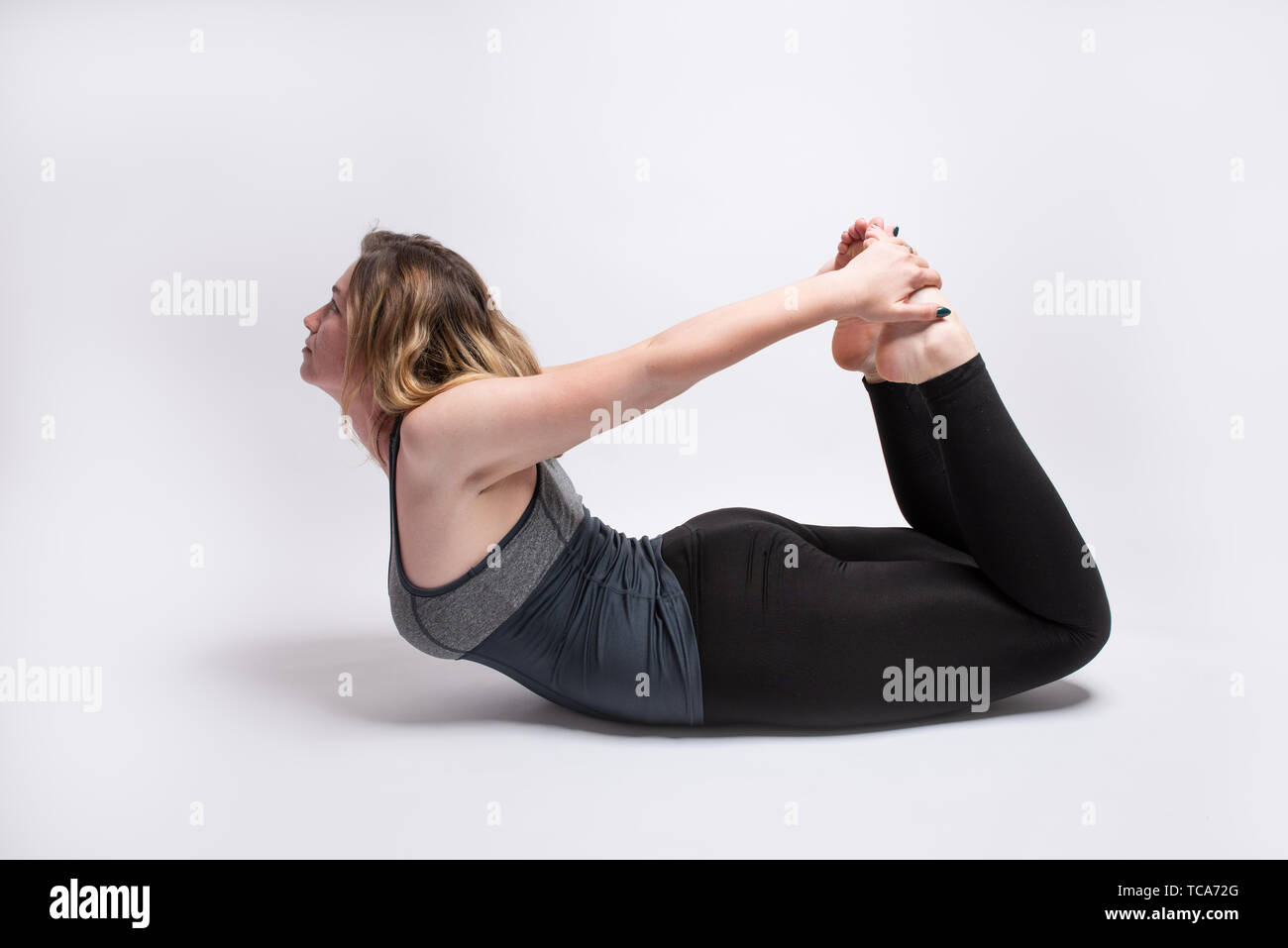 Blonde woman performing Bow Pose Dhanurasana yoga pose Stock Photo Blonde woman performing Bow Pose Dhanurasana yoga pose Stock Photo