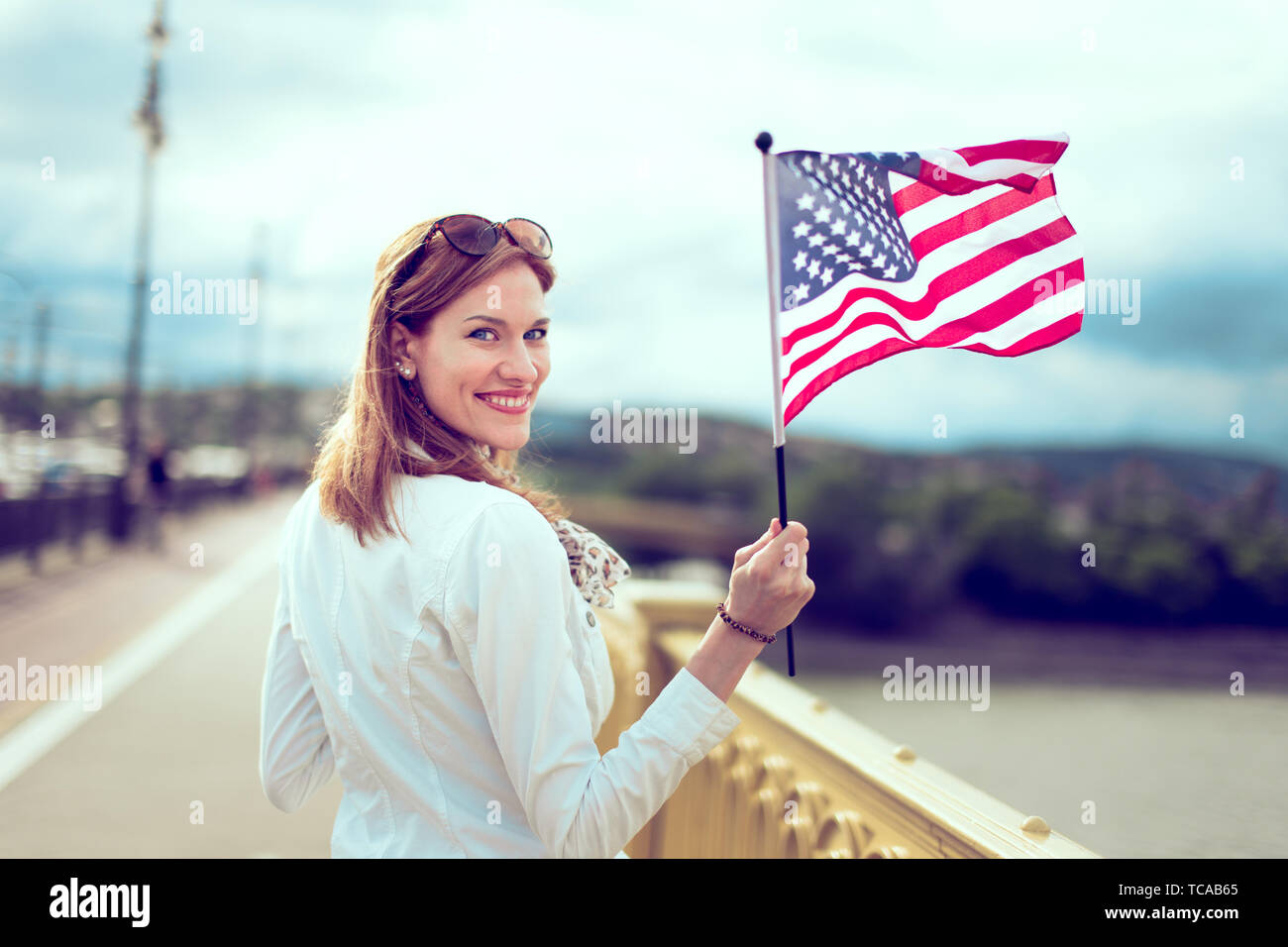 Happy young patriot modern urban woman waving USA flag portrait Stock Photo