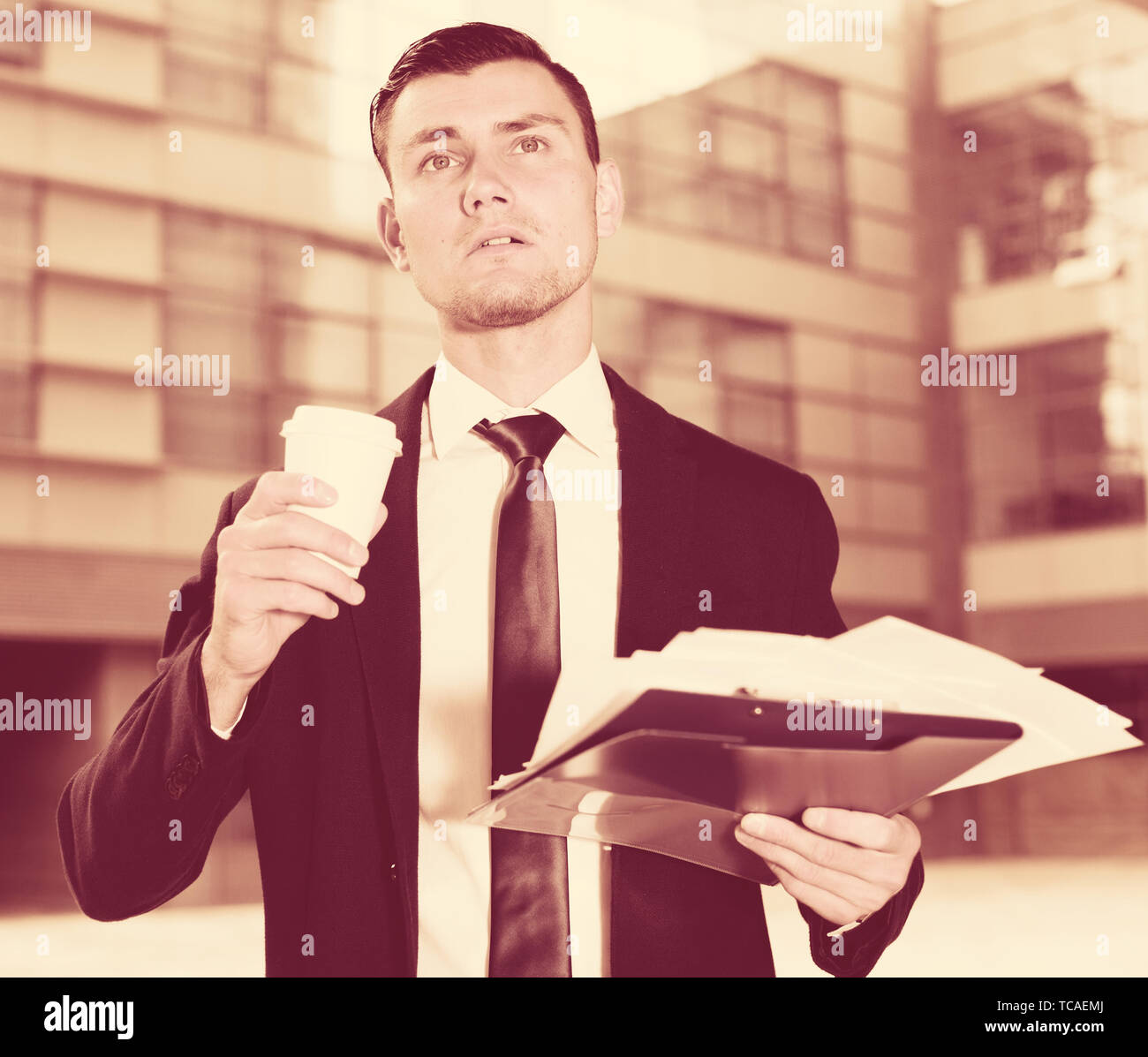 Financial director is examining documents and drinking coffee near