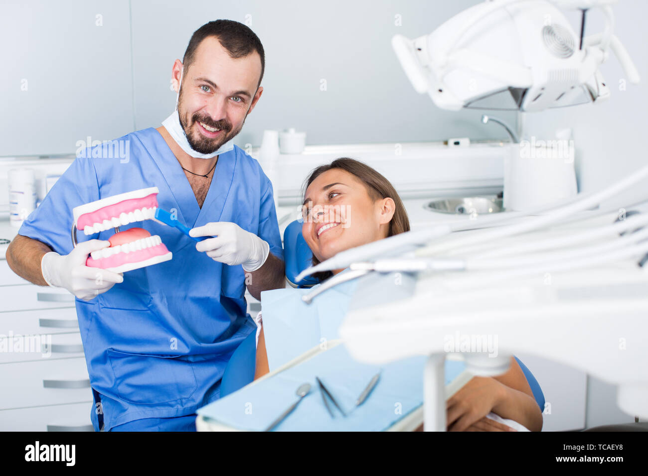 Young doctor in uniform is telling about hygiene of teeth in dental