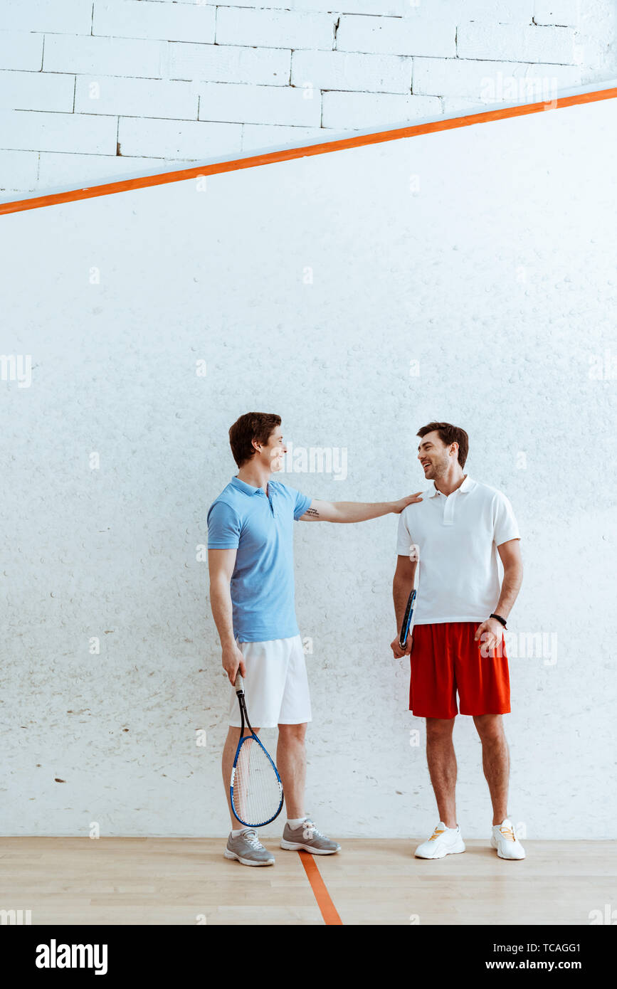 Full length view of squash player putting hand on shoulder of friend Stock Photo