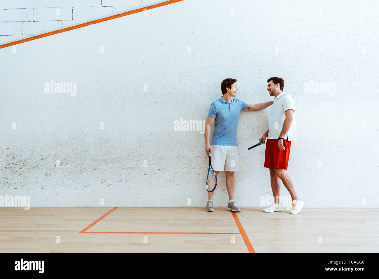 Full length view of squash player putting hand on shoulder of friend Stock Photo