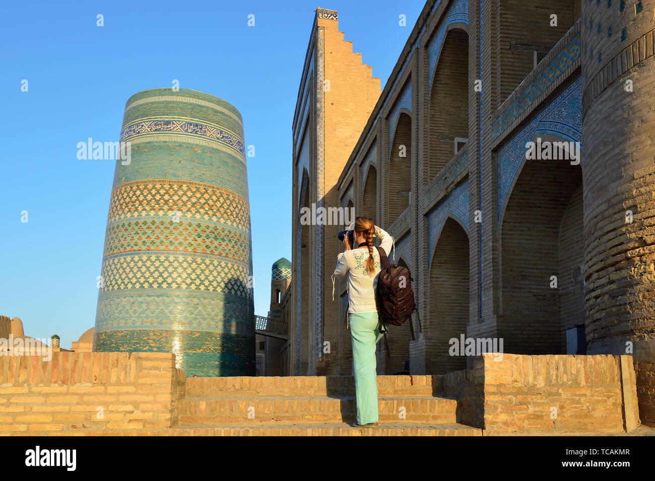 Khiva, Uzbekistan, Tourist on the main square  is photographing ancient monuments of Khiva of architectural pearl on the Silk Route, Kalta Minor Minar Stock Photo