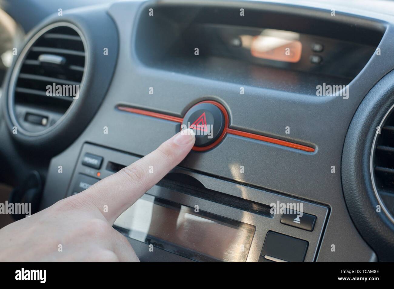 Woman pressing hazard lights button. Inside car view. Stock Photo