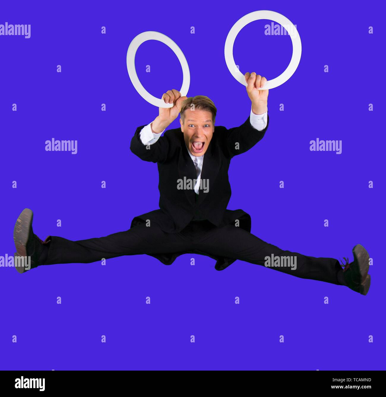 Elegant and happy juggler jumping with two juggling rings on his hands